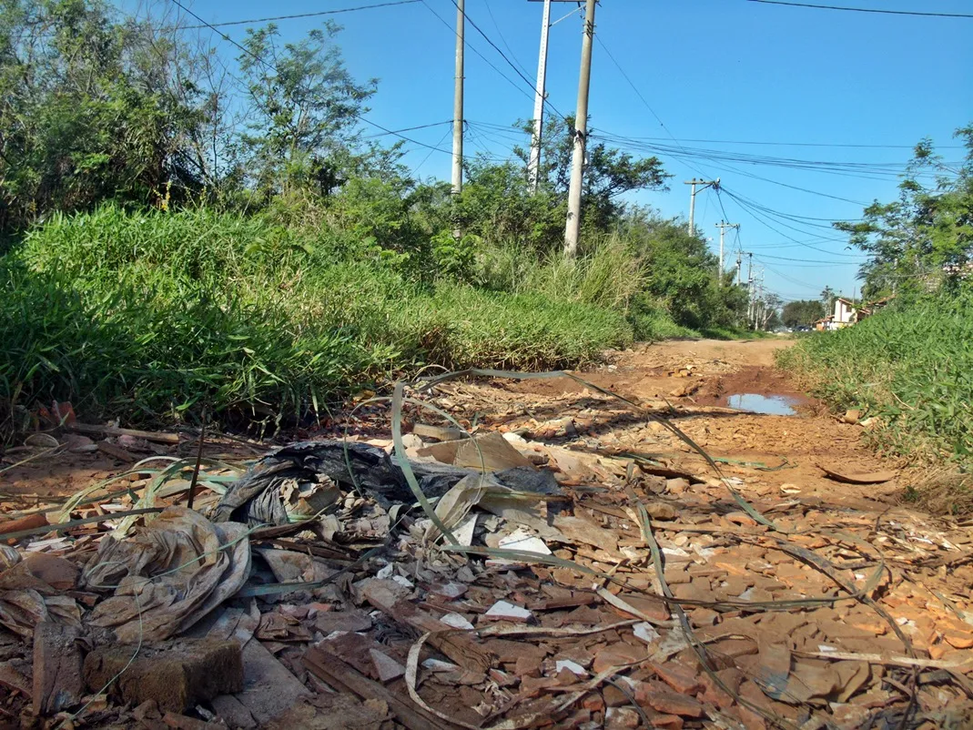 Rua 32: Mato invade a rua cheia de resto de obras. (Foto: João Henrique | Maricá Info)